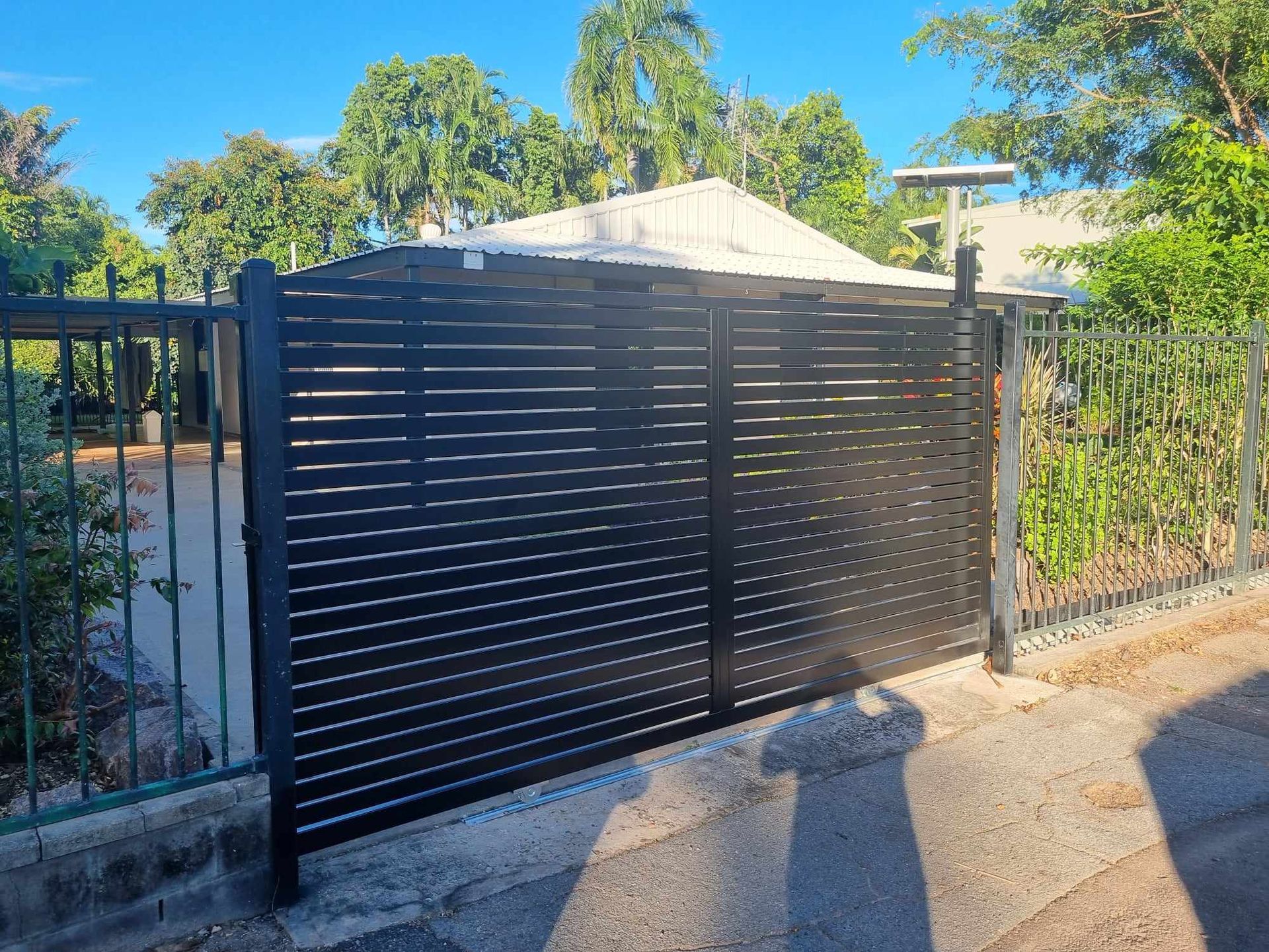 A Close up Of A Black Metal Gate in front of a house — Fence Factory In Berrimah, NT