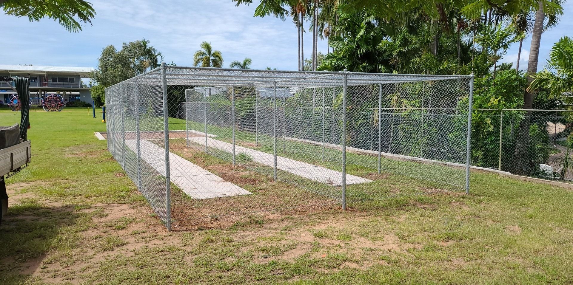 A Chain Link Fence is Sitting in the Middle of a Grassy Field — Fence Factory in Berrimah, NT