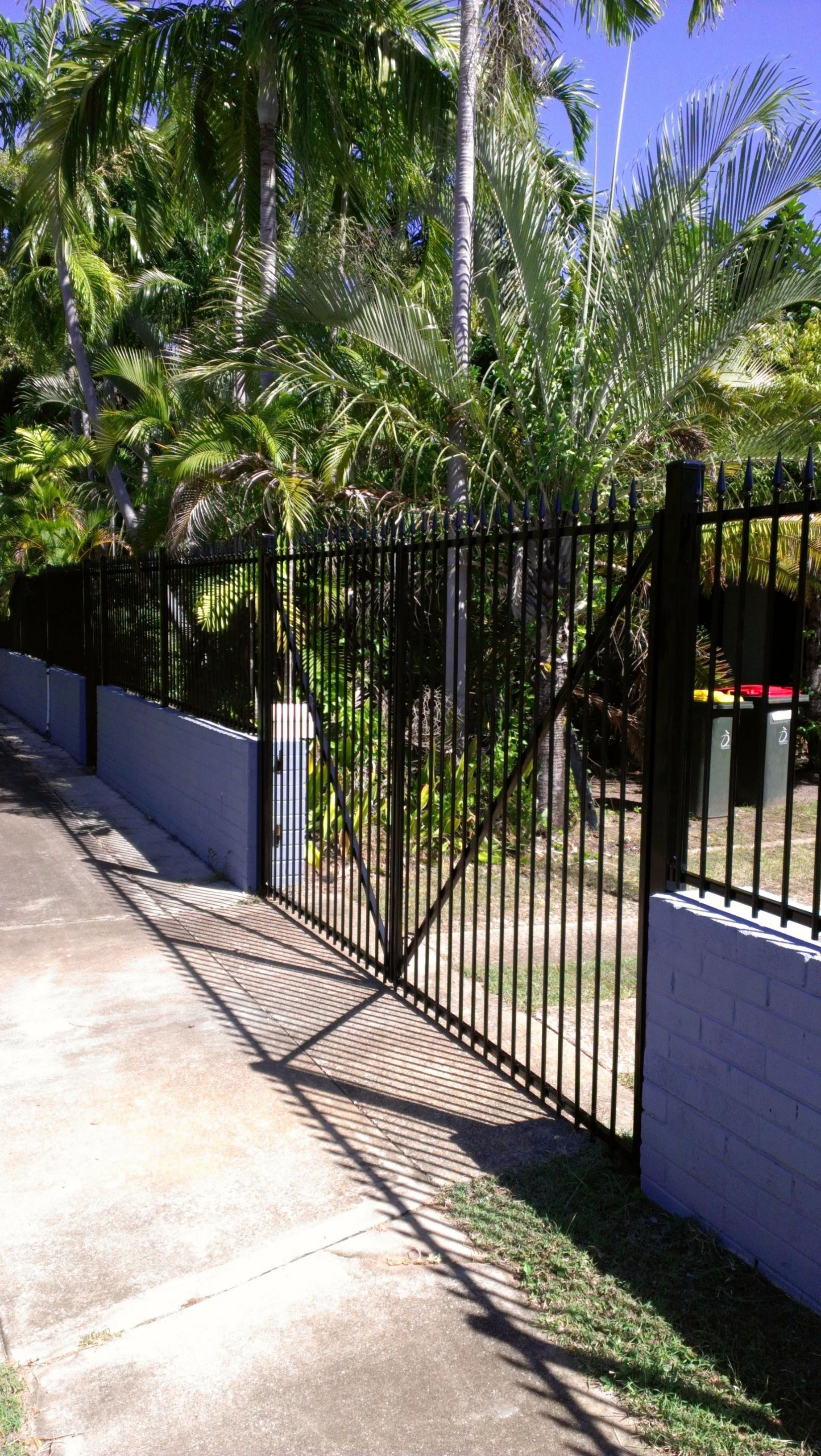 A black metal Gate Is Sitting in Front of A House — Fence Factory In Palmerston, NT