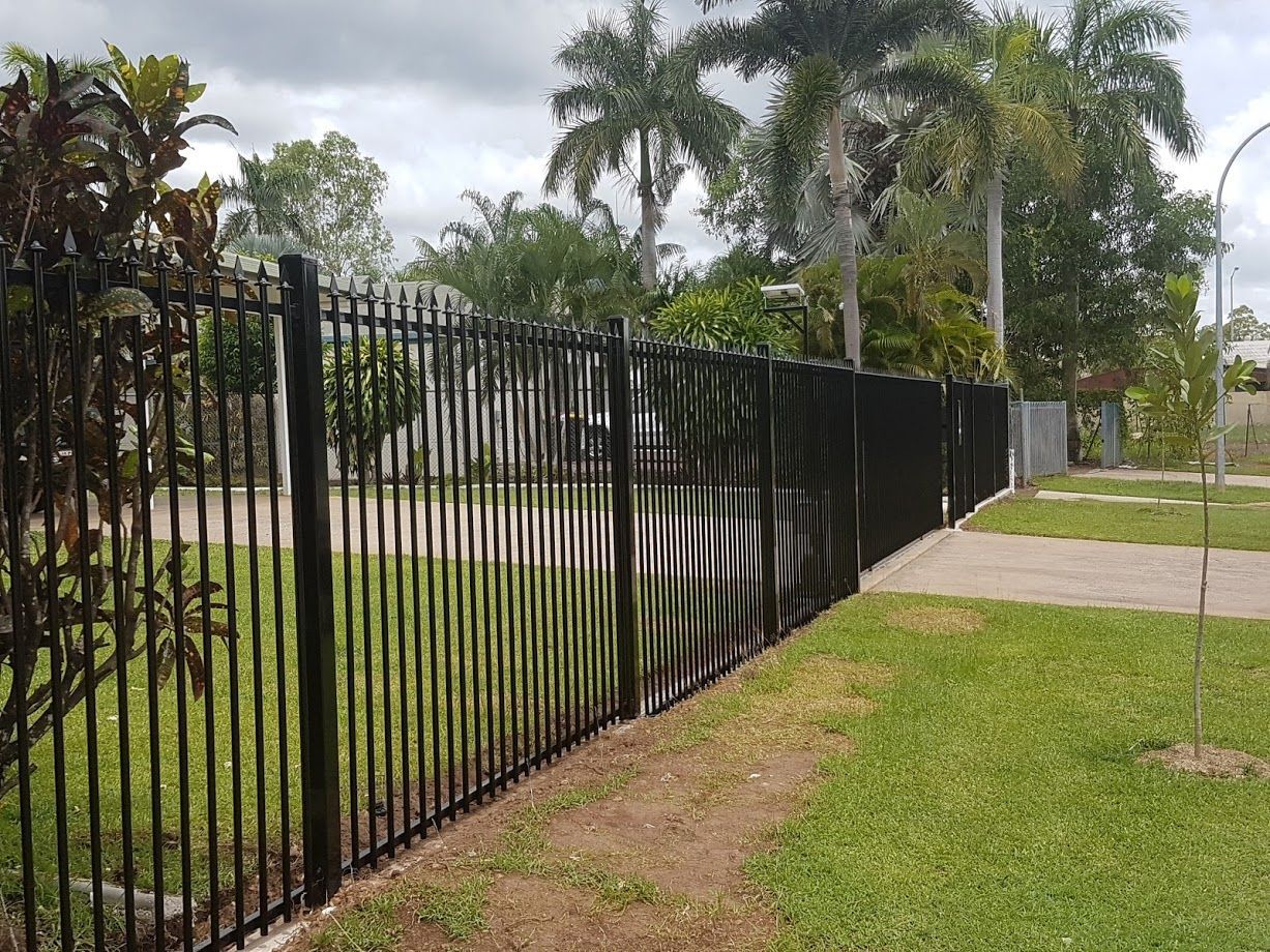 A Black Metal Fence is Surrounding a House and Driveway — Fence Factory In Katherine, NT