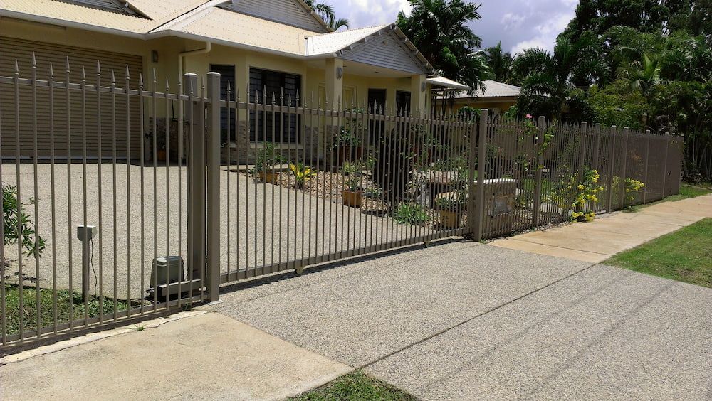 A Sliding Gate Is Open to A Driveway in Front of A House — Fence Factory In Berrimah, NT