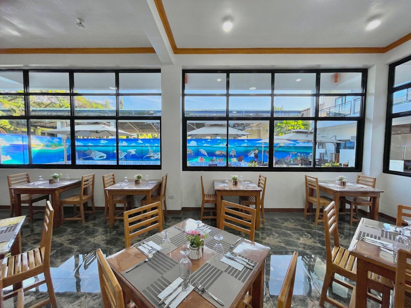 A restaurant with tables and chairs and a pool in the background.
