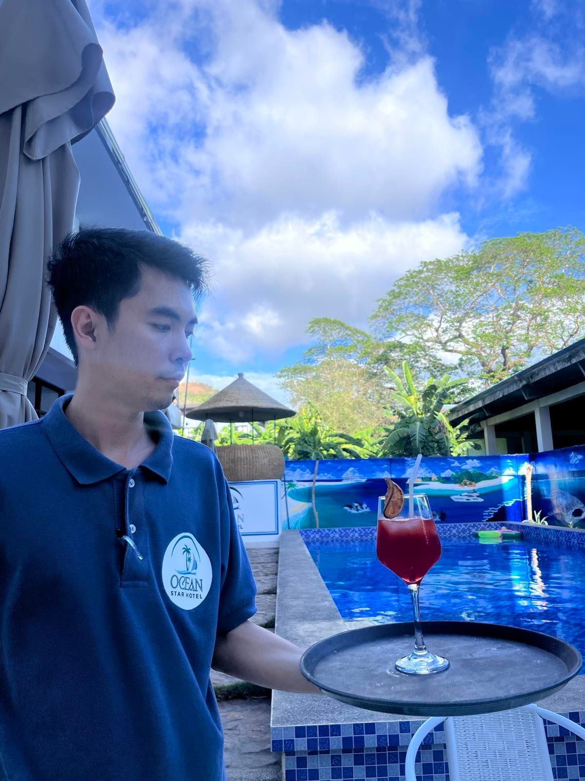 A man is holding a tray with a glass of wine on it.