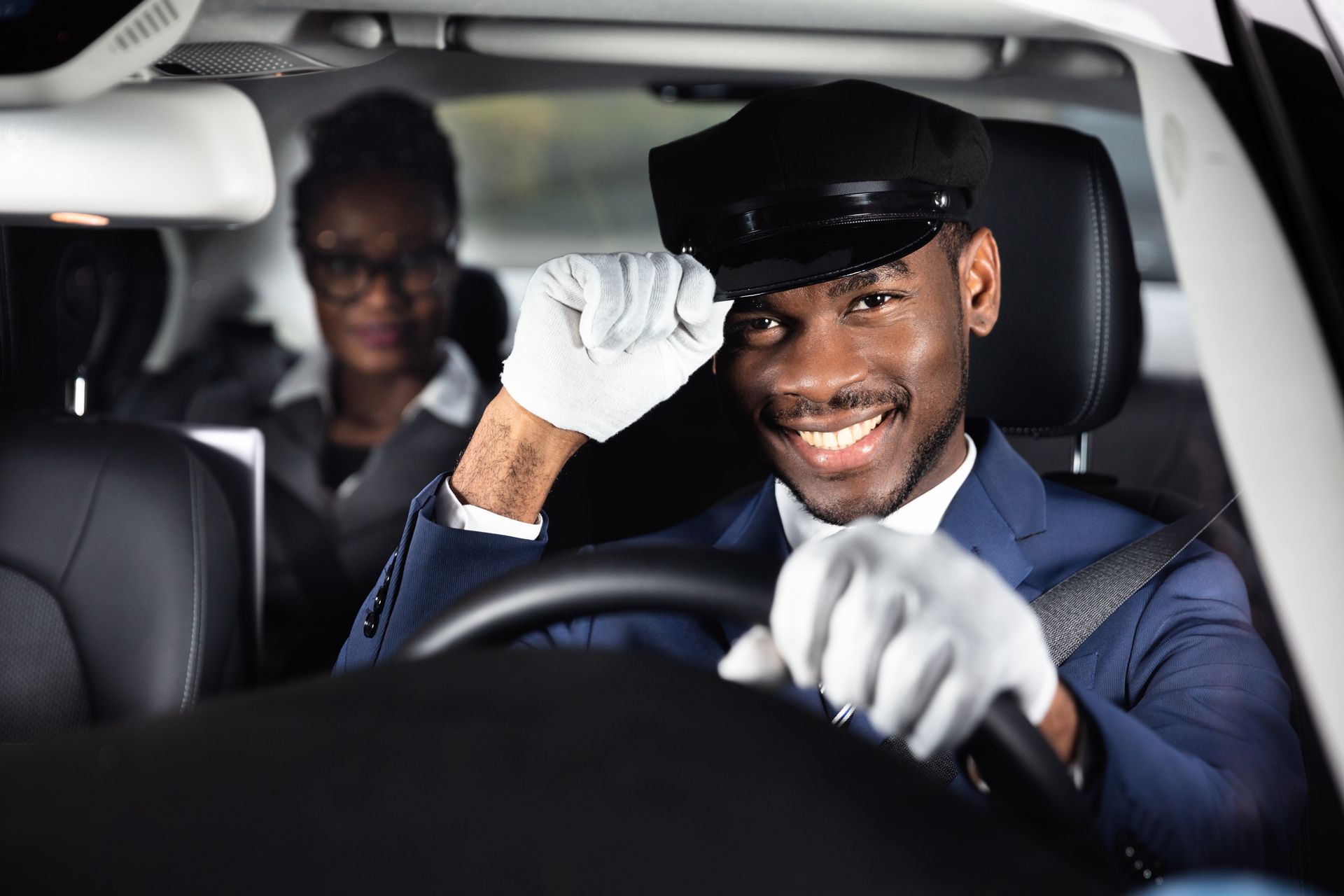 A man in a suit is driving a car with a woman in the back seat