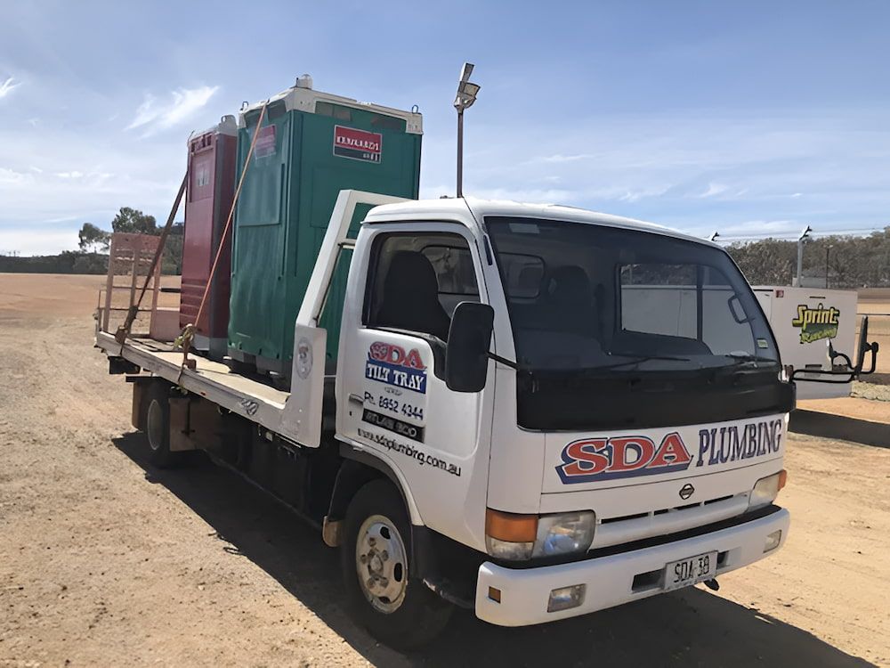 White truck transporting portable toilets on a sunny day. — SDA Plumbing in Alice Springs, NT