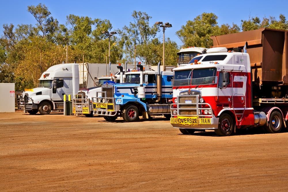 Trucks Parked on Dirt Lot Under Blue Sky — SDA Plumbing in Alice Springs, NT