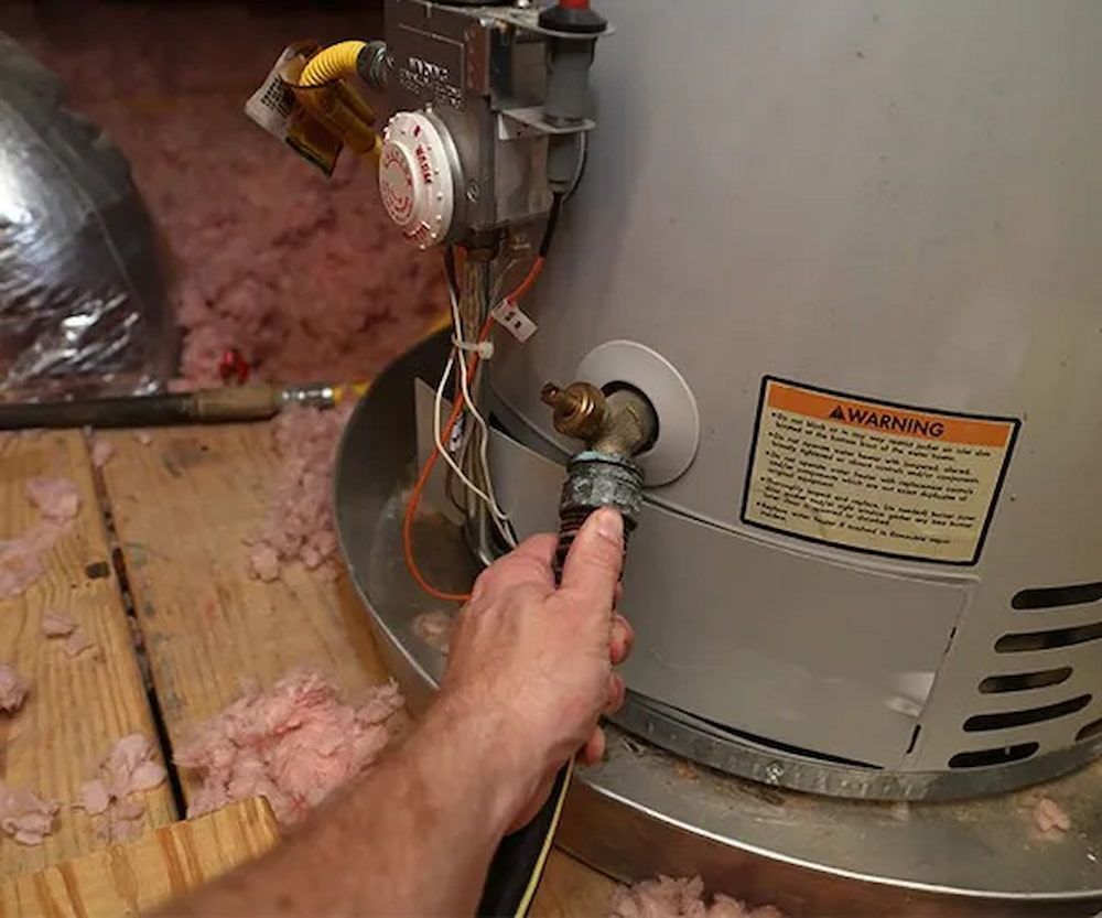 Hand Connecting a Hose to a Water Heater Drain Valve in a Utility Room — SDA Plumbing in Alice Springs, NT