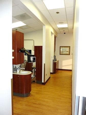 Empty office hallway with wood flooring, sink area, and framed wall art