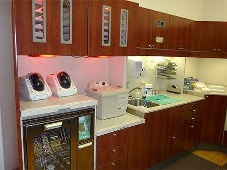 Wood-paneled kitchen display with countertops, sink, and appliances under warm cabinet lighting