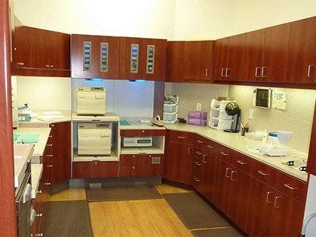 Modern kitchen with dark wood cabinets, beige countertops, and stainless appliances on a wooden floor