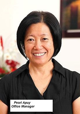 Portrait of Pearl Apuy, Office Manager, smiling in a black top indoors