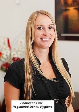 Portrait of smiling dental hygienist in black top with name tag in an office setting