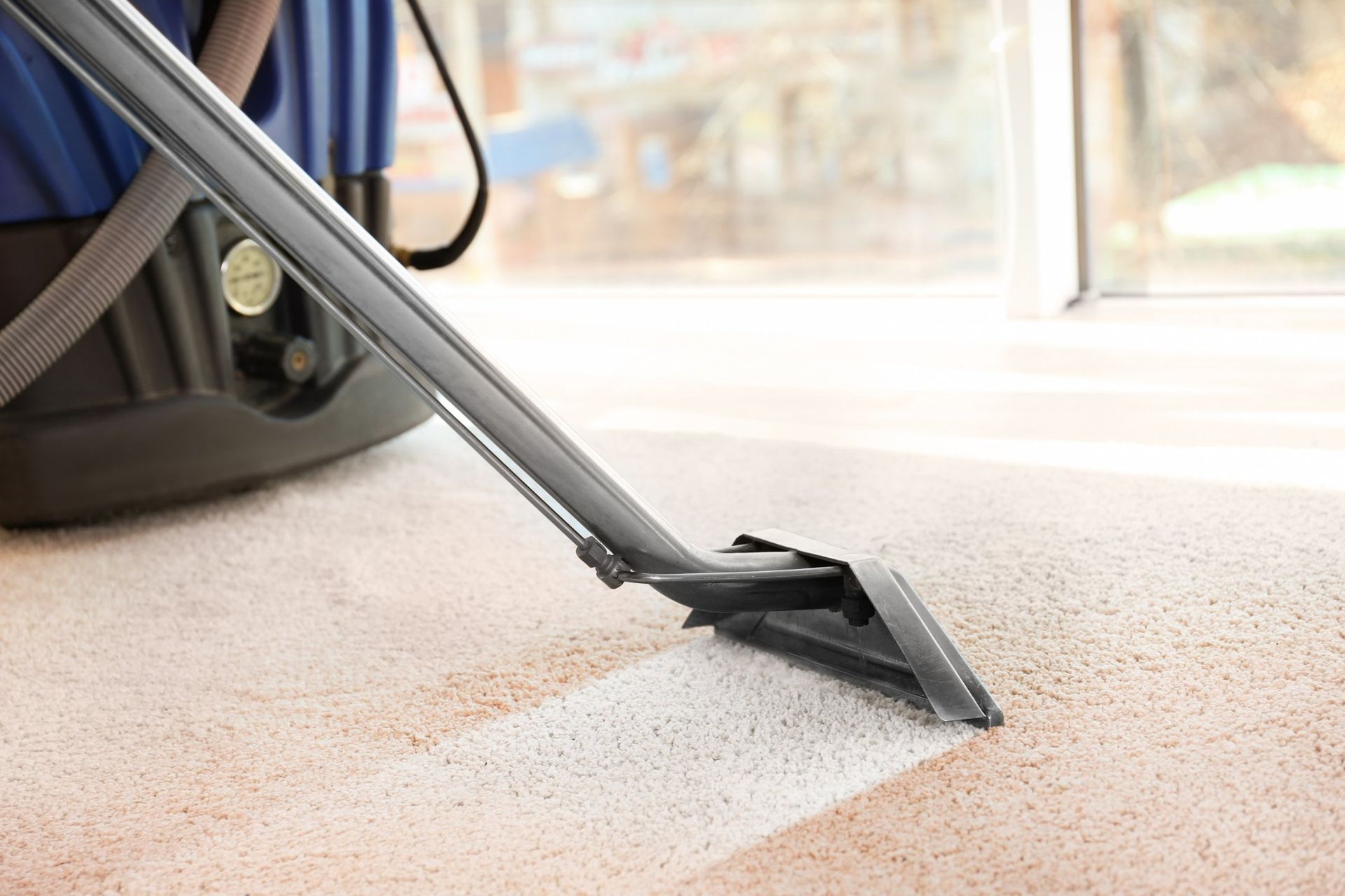 A man in a blue shirt is vacuuming a carpet