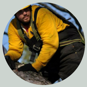 Person in a yellow jacket and helmet climbing over a rock outdoors