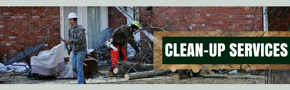 Workers cleaning debris beside a brick wall with a sign reading “CLEAN-UP SERVICES”