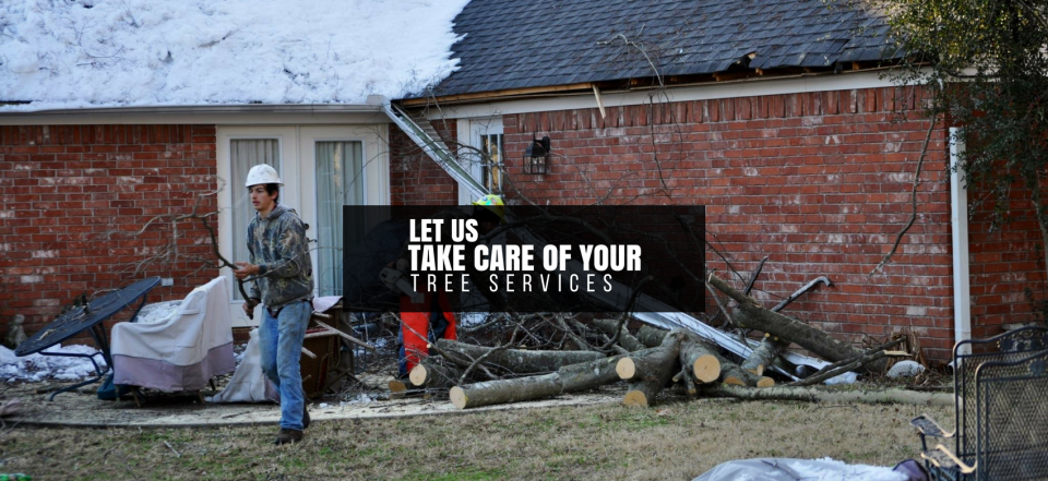 Worker standing by a brick house roof repair with a sign reading “Let us take care of your tree services.”