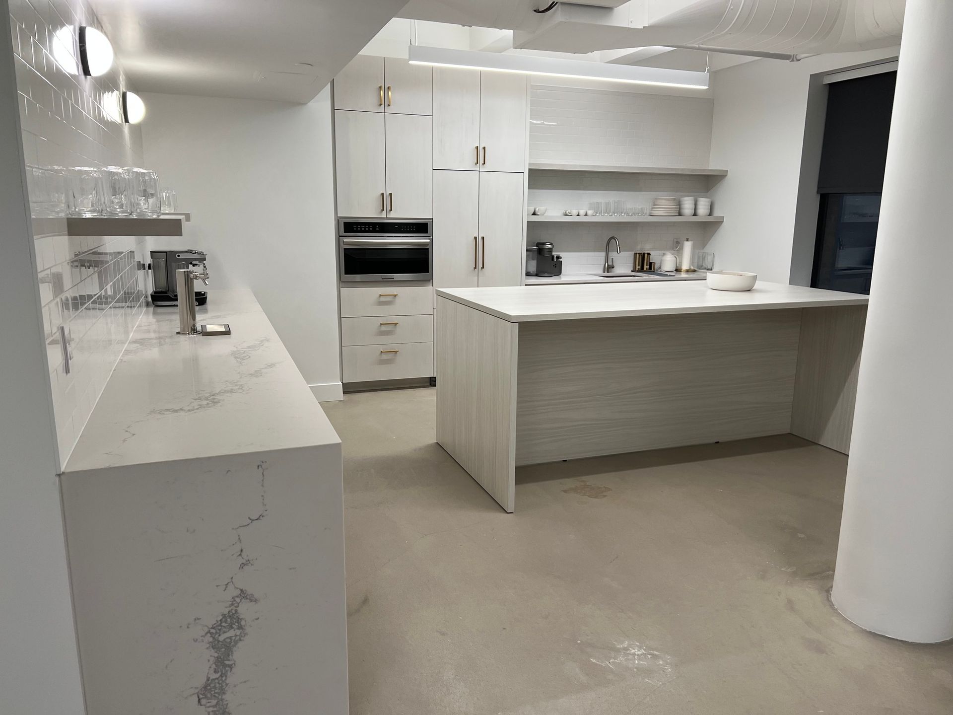 Modern white kitchen with a marble countertop island, cabinets, and appliances.