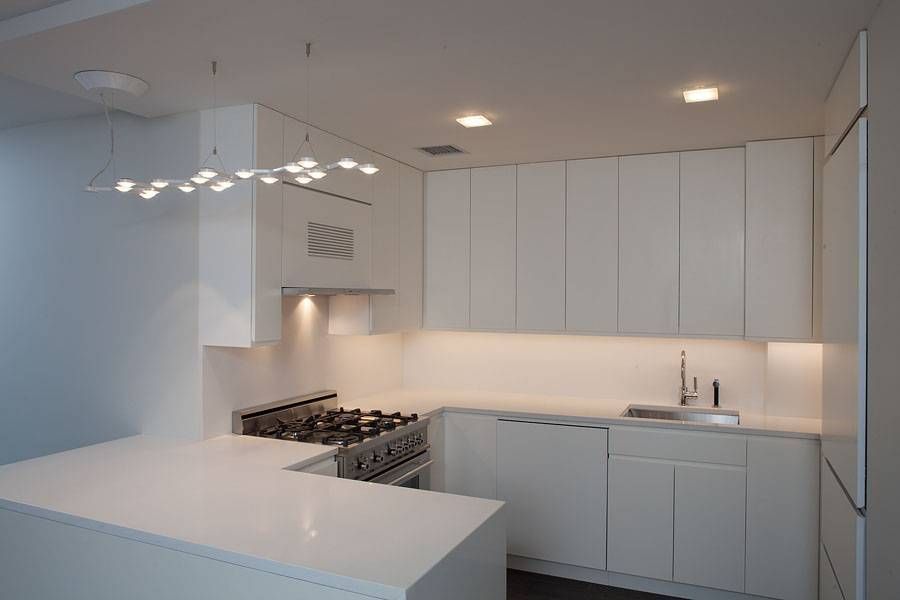 Modern all-white kitchen with a countertop and cabinets. A stainless steel stove is present.