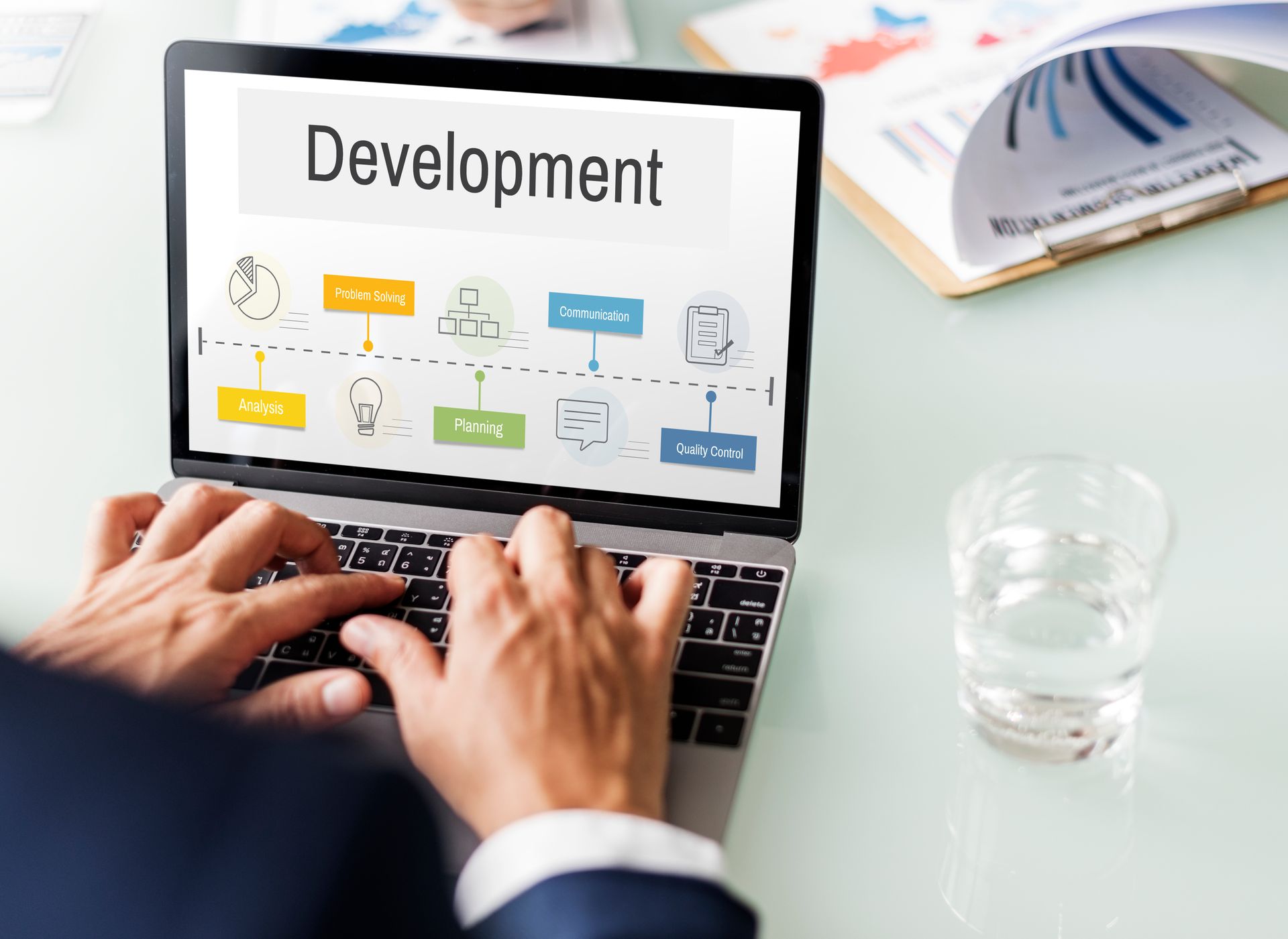 Hands typing on a laptop showing “Development” with colorful workflow icons on screen