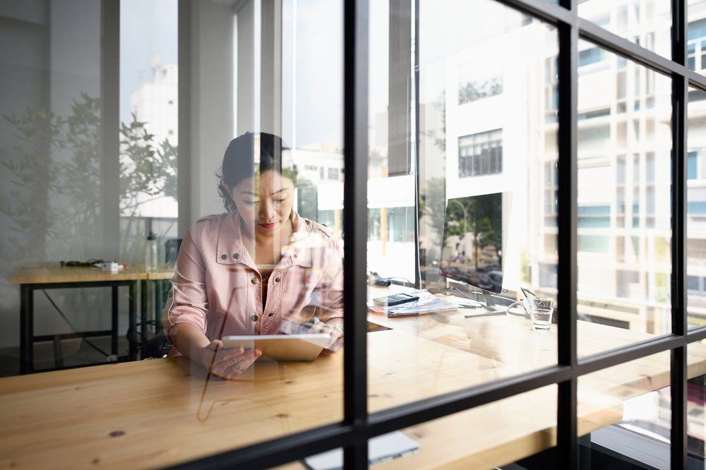 A Woman Working at a Desk, Viewed Through a Glass Partition A Woman Working at a Desk, Viewed Through a Glass Partition