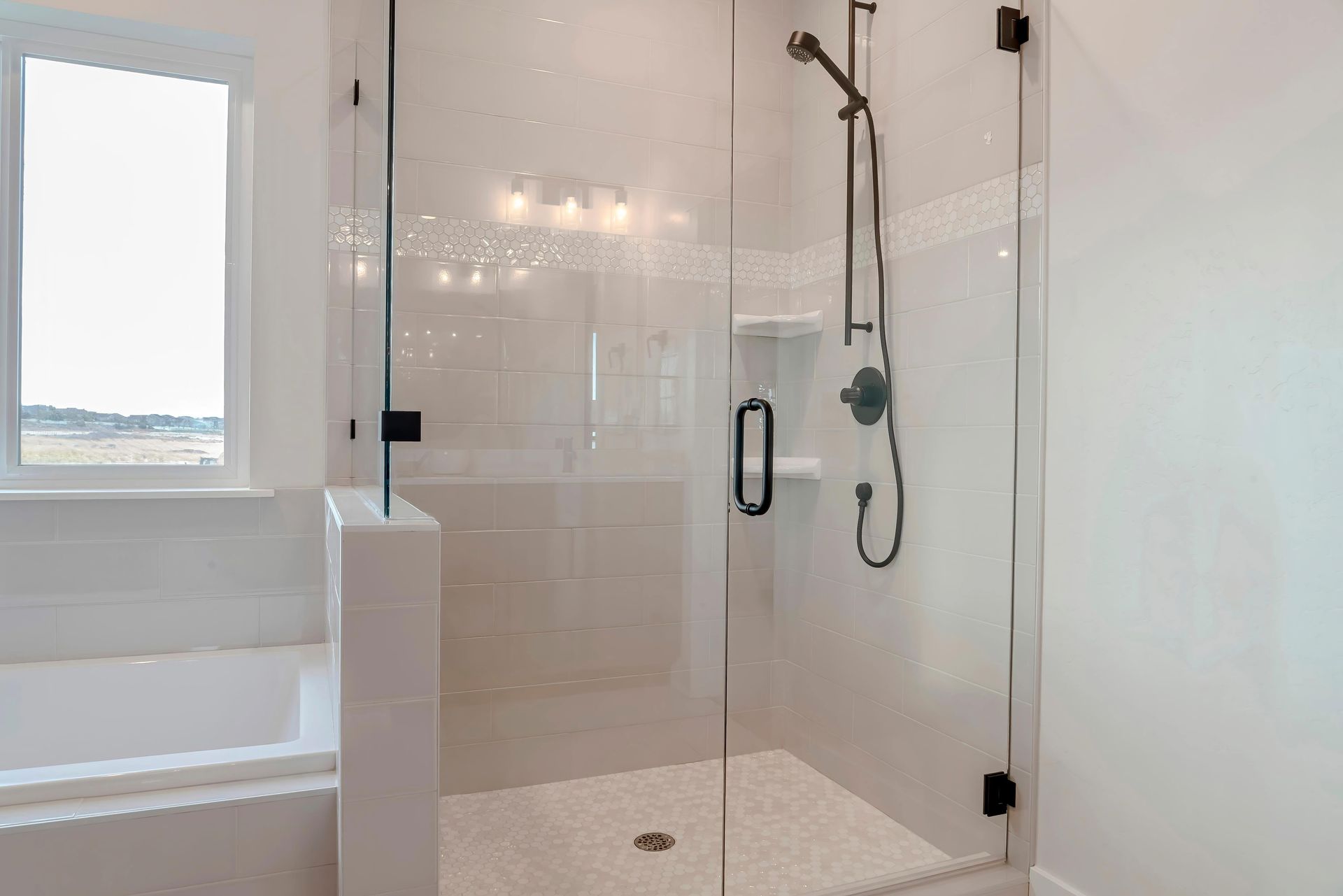 A bathroom shower stall made of glass, inside a white bathroom with a window. A bathroom shower stall made of glass, inside a white bathroom with a window.