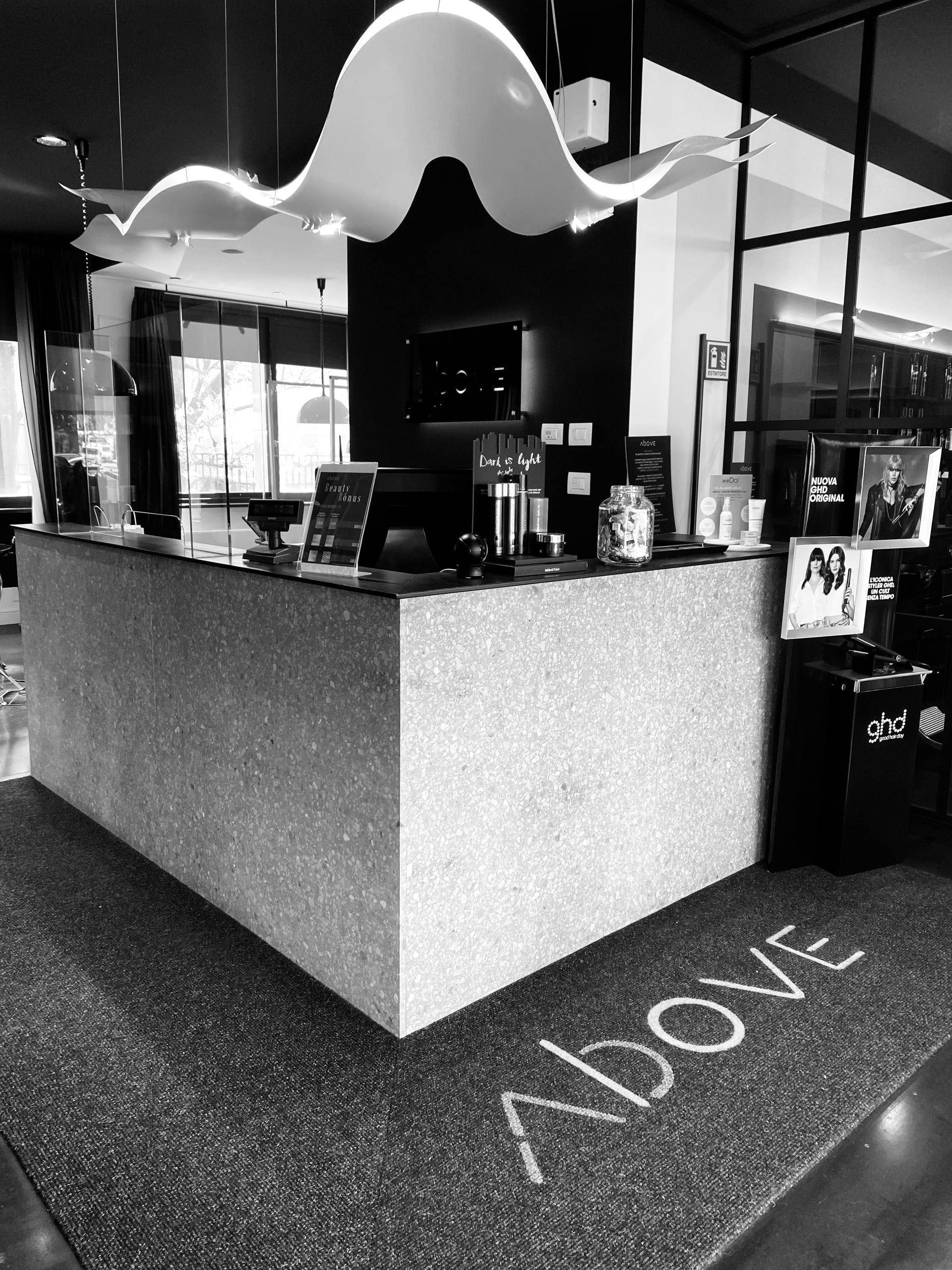 Un bancone della reception con una lampada a sospensione bianca ondulata sopra e la parola
