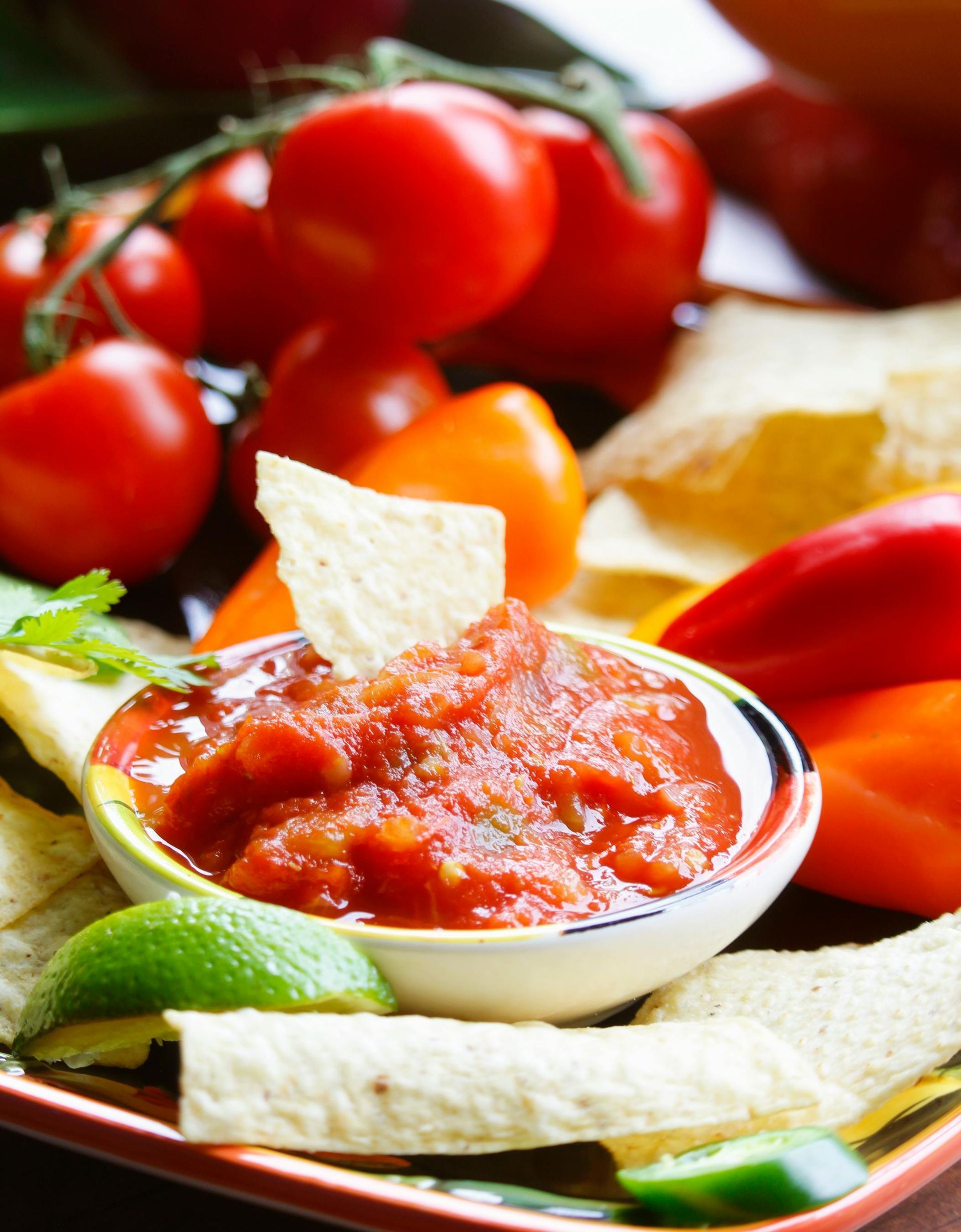 Tazón de salsa con totopos y tomates.