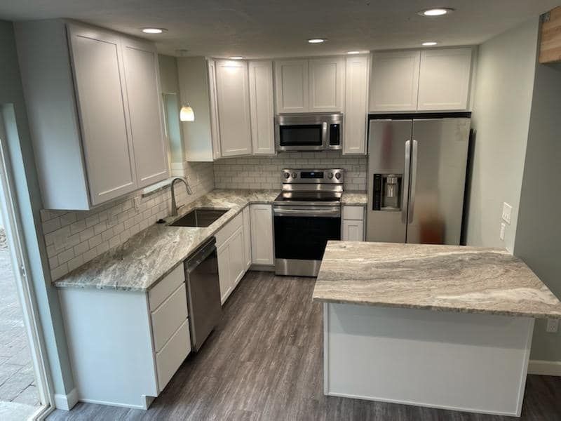 Modern kitchen with white cabinets, granite counters, stainless appliances, and a central island