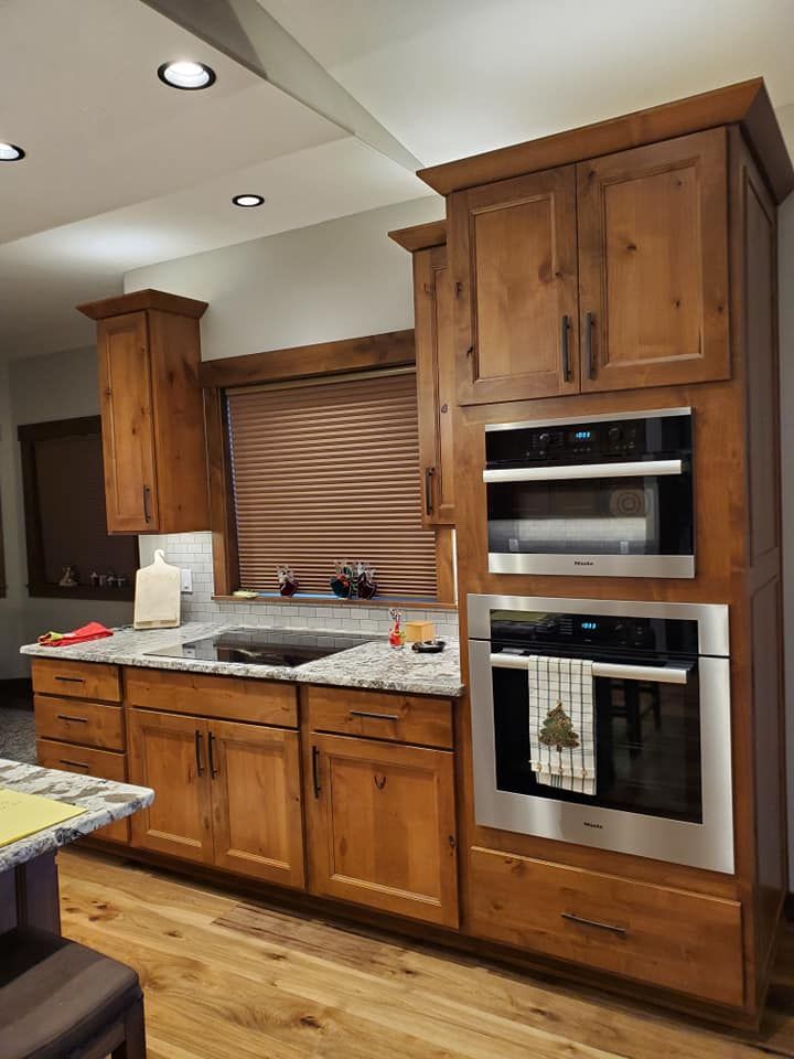 Modern kitchen with wood cabinets, granite counters, stainless oven, and a window with closed blinds