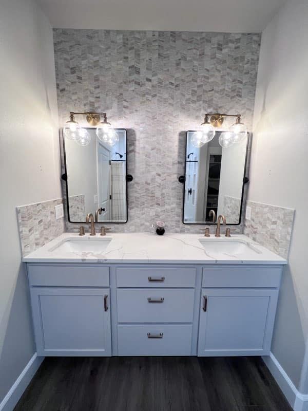Modern bathroom vanity with double sinks, blue cabinets, mirrors, and wall sconces