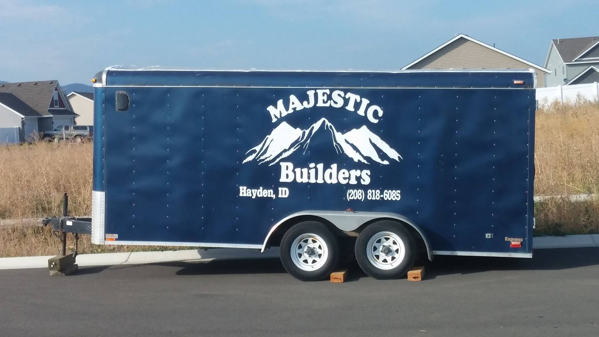Blue Majestic Builders trailer parked on a street with mountains and houses in the background