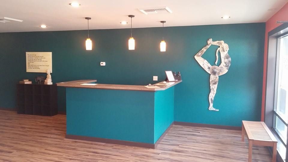 Modern lobby with teal accent wall, reception desk, pendant lights, and a dancer wall sculpture.