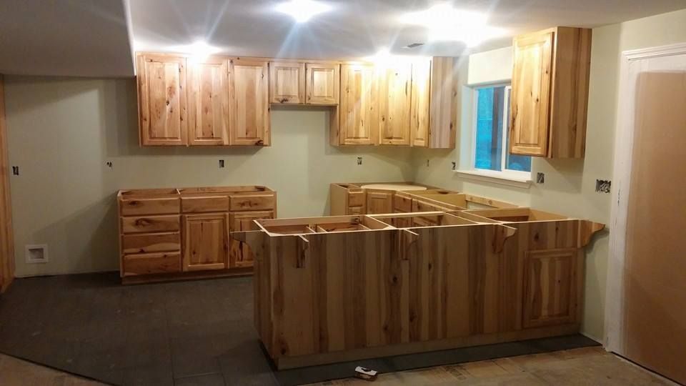 Unfinished kitchen with light wood cabinets and island under bright ceiling lights