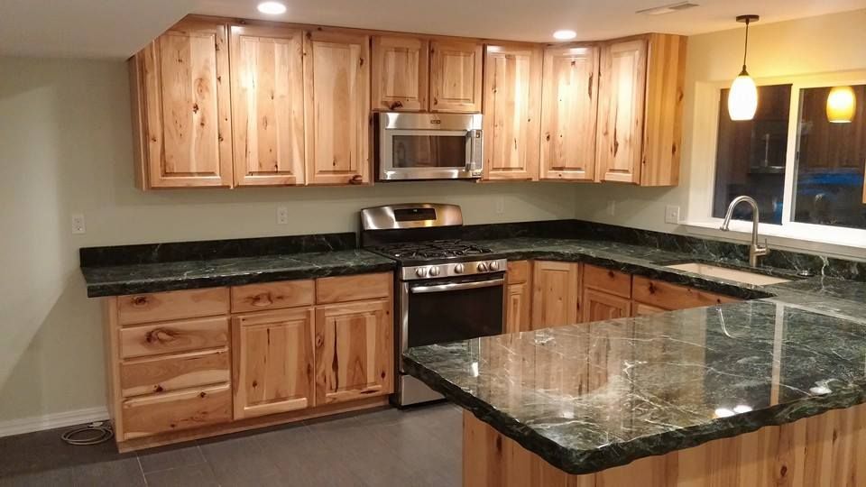 Modern kitchen with wood cabinets, black granite countertops, stainless steel appliances, and a large island.