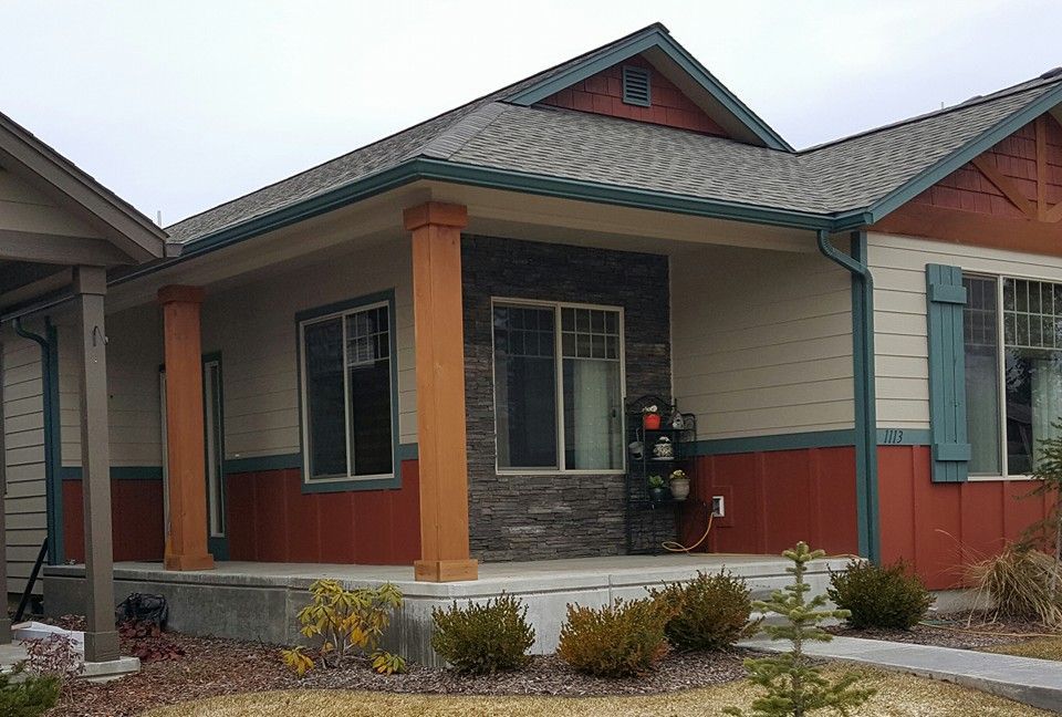 Single-story house with red and gray siding, green roof, and front porch.