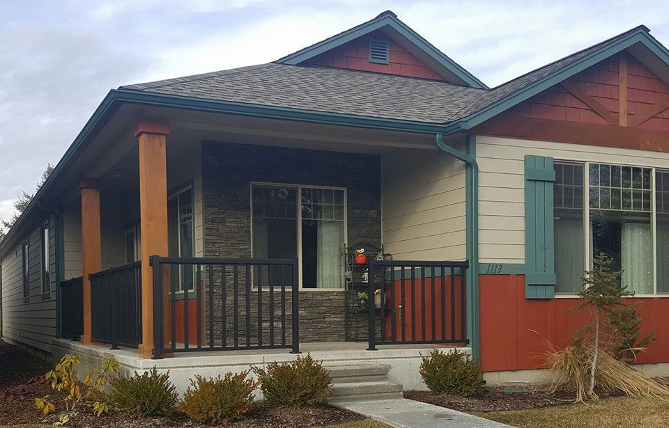 Small house with a covered porch, red trim, and a ramp at the entrance