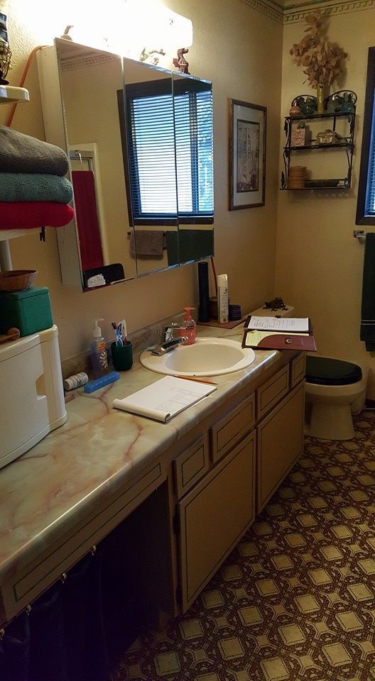 Small bathroom with sink, mirror, toiletries, and patterned floor tiles.