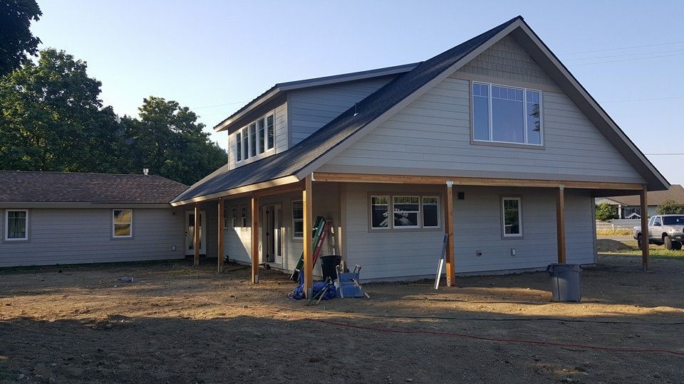 Single-story house with a covered front porch and a partly finished yard at sunset