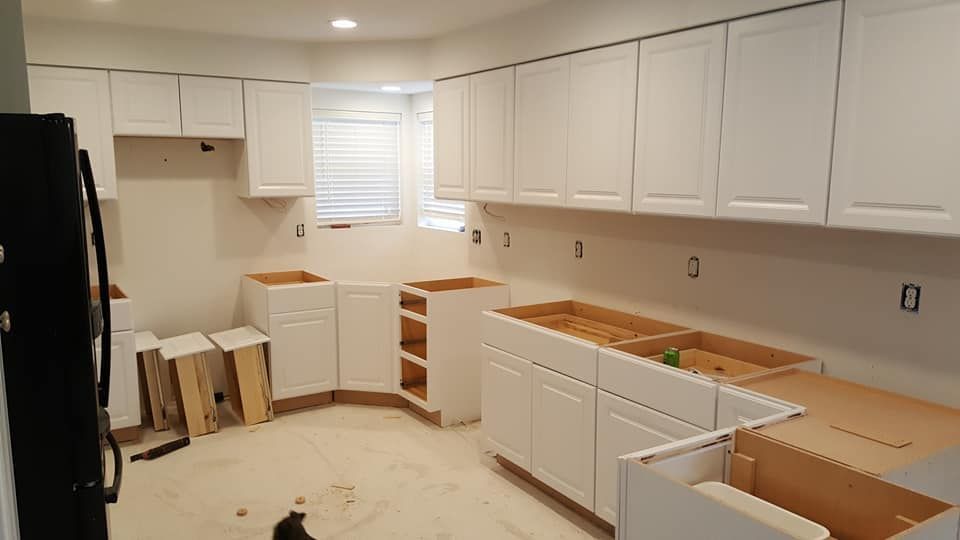 Unfinished white kitchen with cabinets, countertops, and boxes during renovation