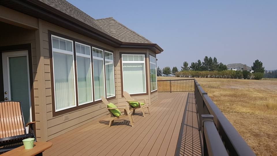 House deck with green chairs overlooking a dry field under a clear sky