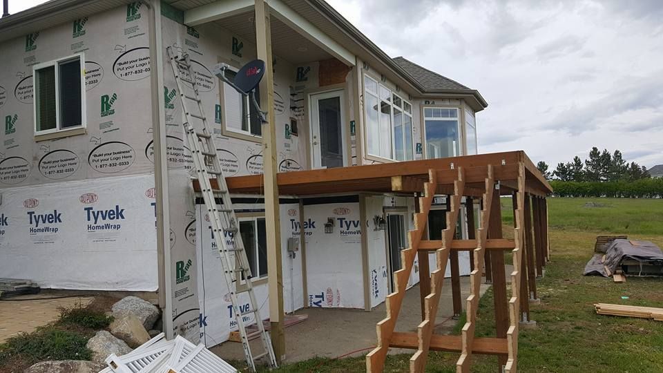 House under construction with Tyvek wrap and a wooden porch frame on a grassy lot