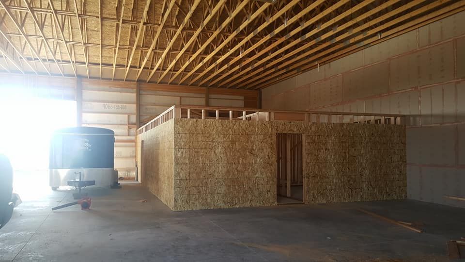 Bus parked inside a bare wooden garage with exposed beams and plywood walls.