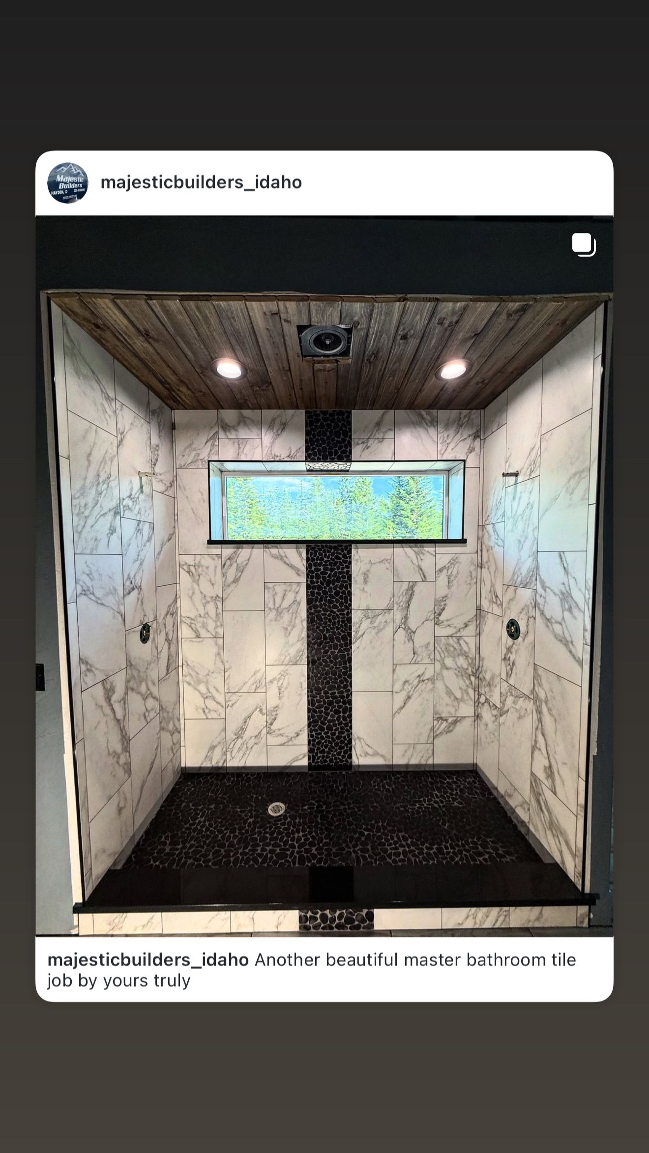 Small tiled shower stall with dark floor and a narrow window showing greenery.