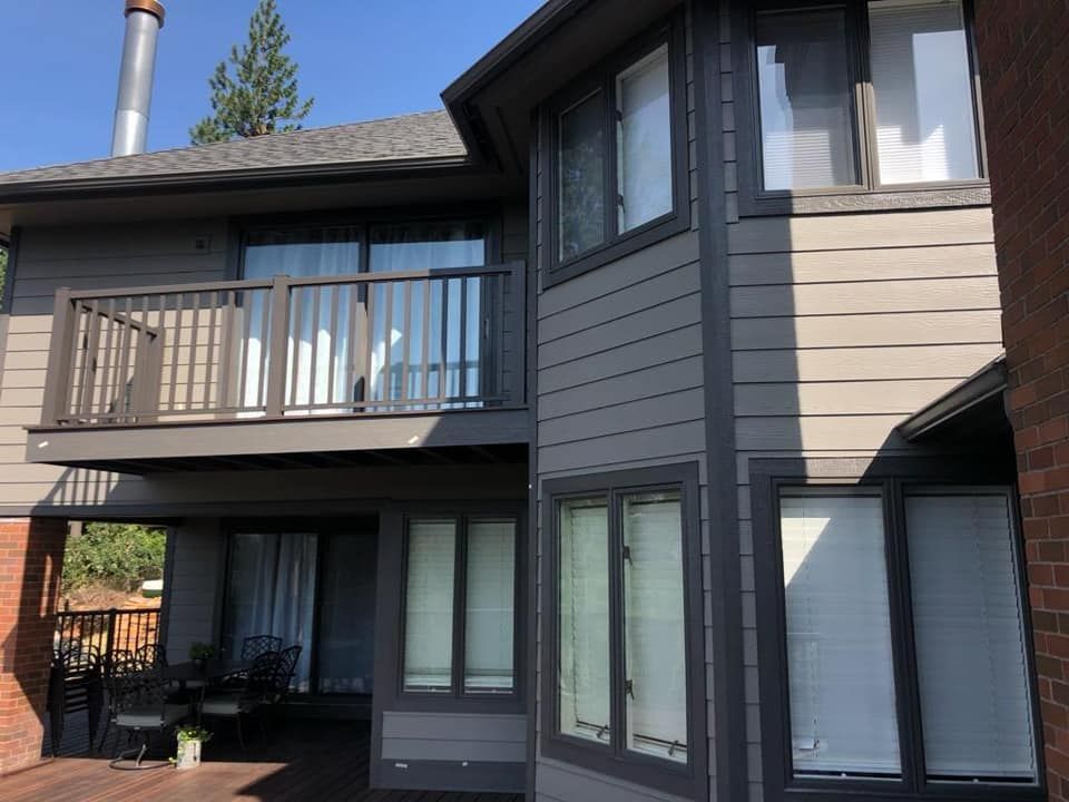 Two-story dark gray house exterior with balconies and large windows
