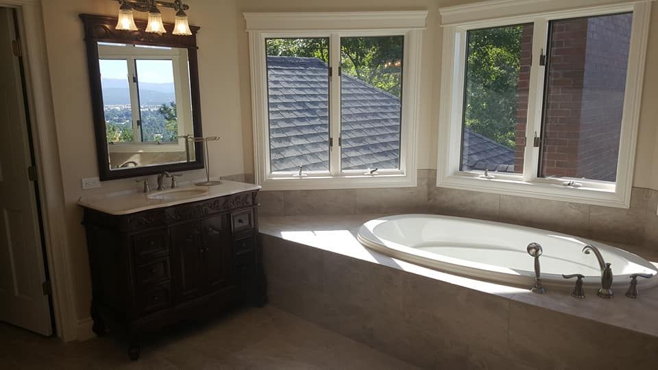 Bathroom with a large corner soaking tub, double vanity, and bay windows letting in daylight