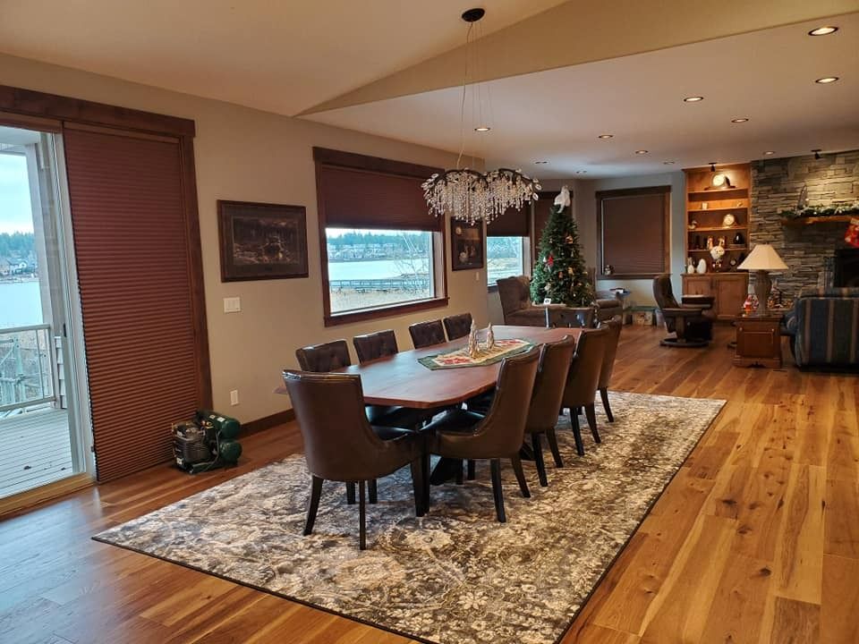 Spacious dining room with a wooden table, chairs, chandelier, Christmas tree, and stone fireplace.