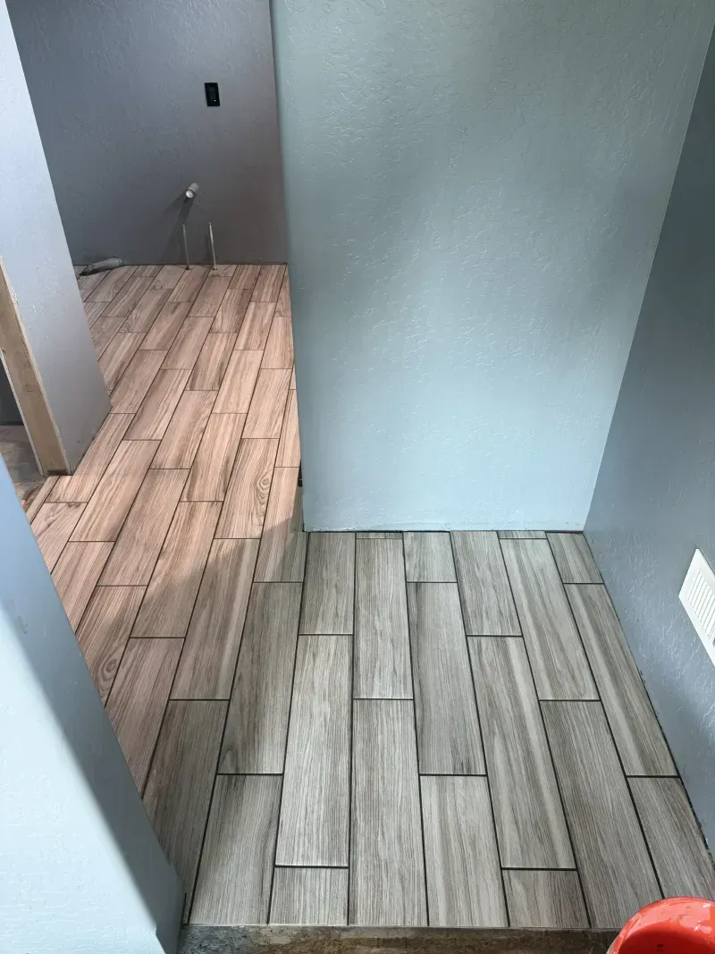 Empty hallway with gray walls and patterned tile flooring, seen from a doorway.