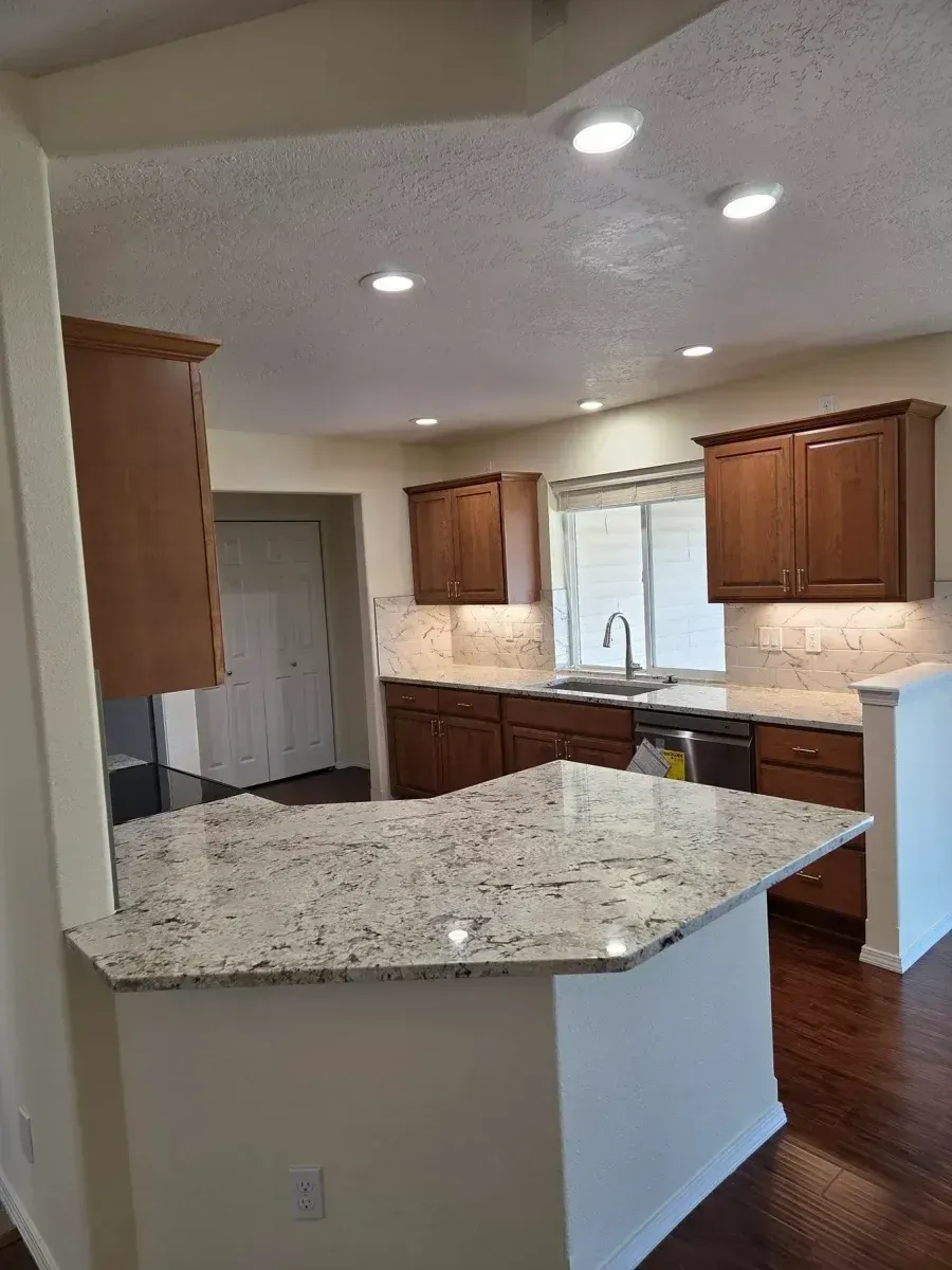 Modern kitchen with granite island, wood cabinets, recessed lights, and hardwood floors