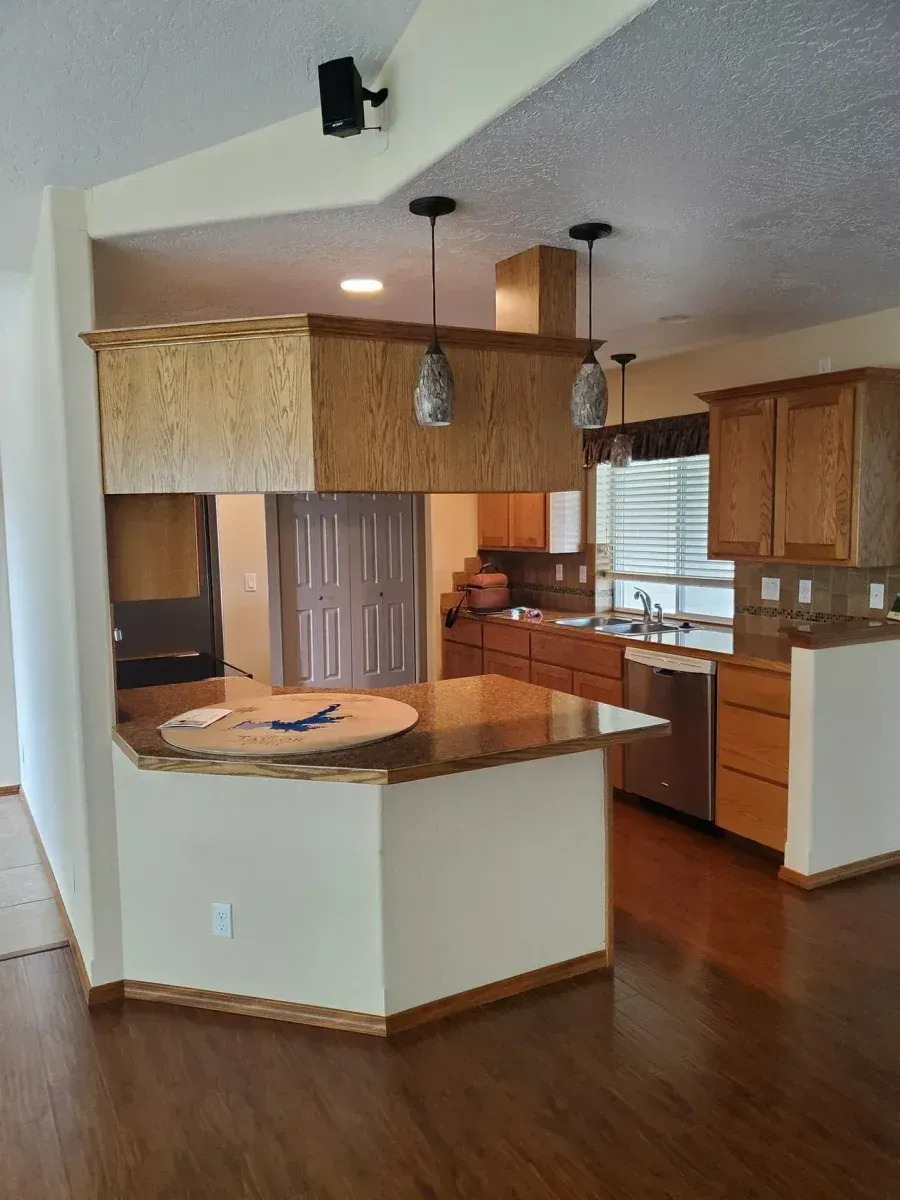Kitchen with white island, wood cabinets, granite counters, and pendant lights