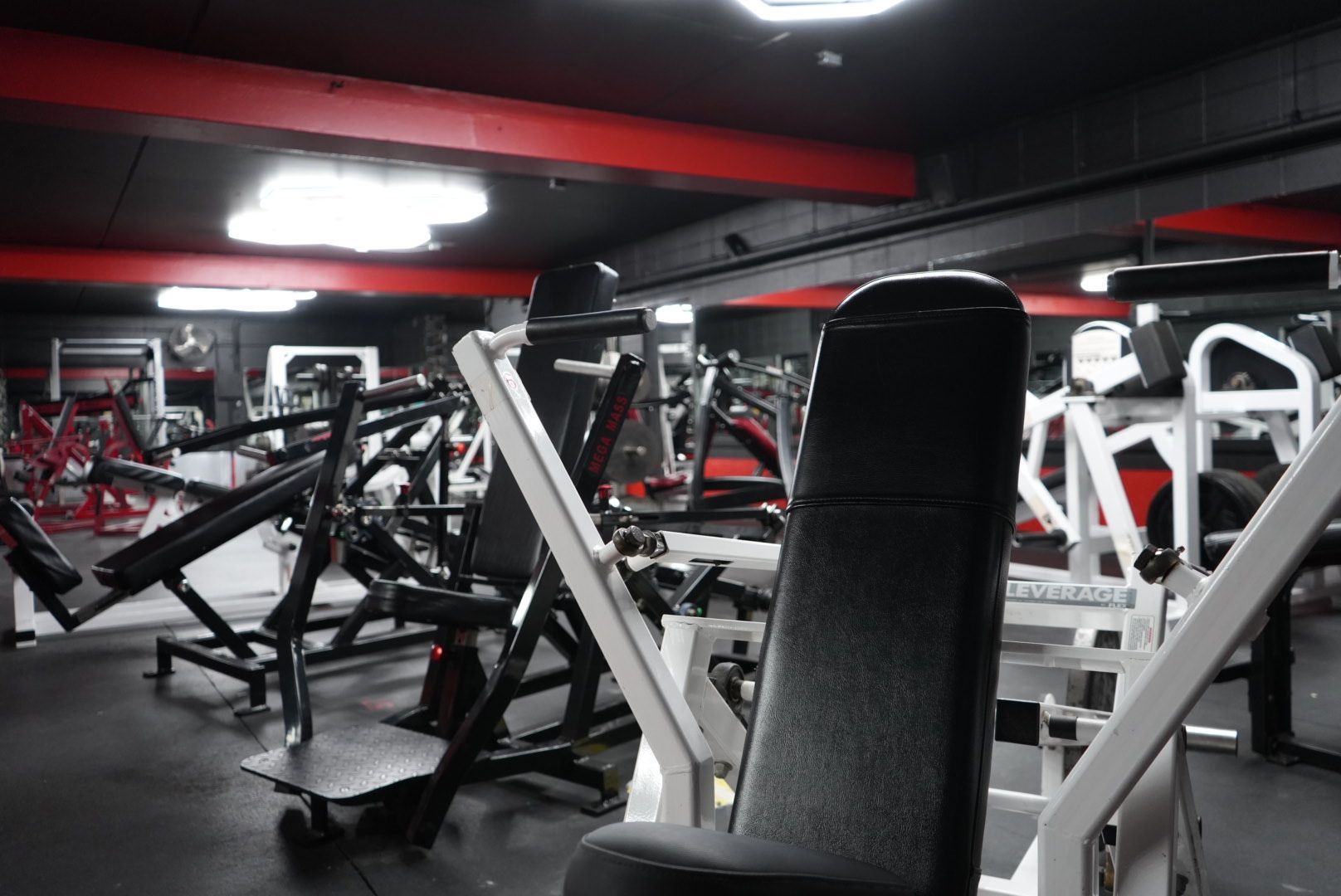 Gym interior with weight machines and benches under red and black lighting